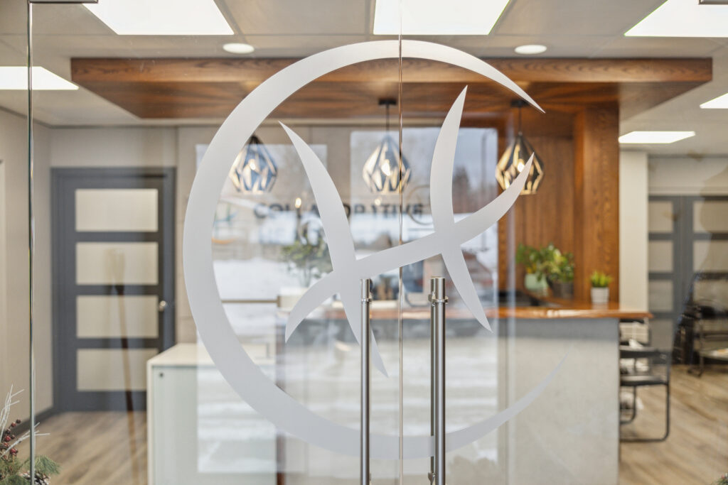 View of the clinic’s reception area from outside a glass door, with the etched Collaborative Health Group logo in focus on the door.