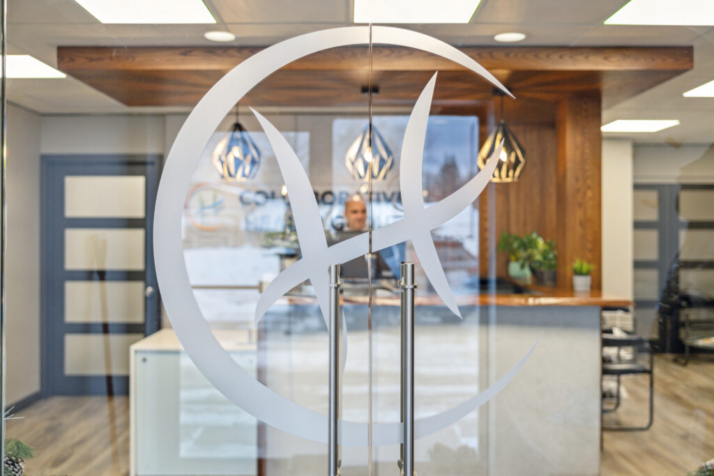 Reception area seen through a glass door with the Collaborative Health Group logo decal; Peter stands behind the front desk.